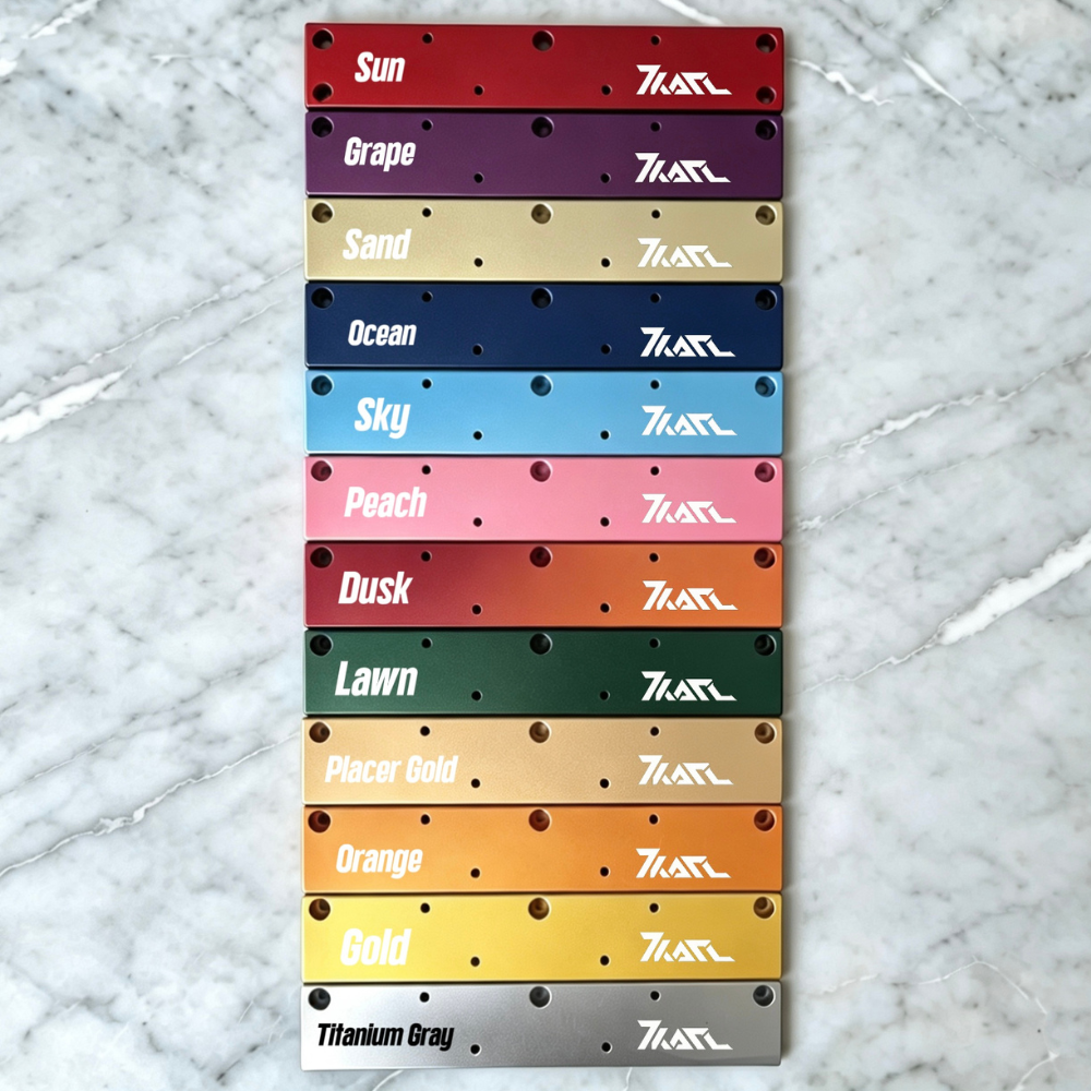 KARL Extension Spacer: Stack of anodized aluminum spacers in 12 vibrant colors (Sun red, Grape purple, Sand beige, etc.) with multiple holes and KARL logo, displayed on marble.