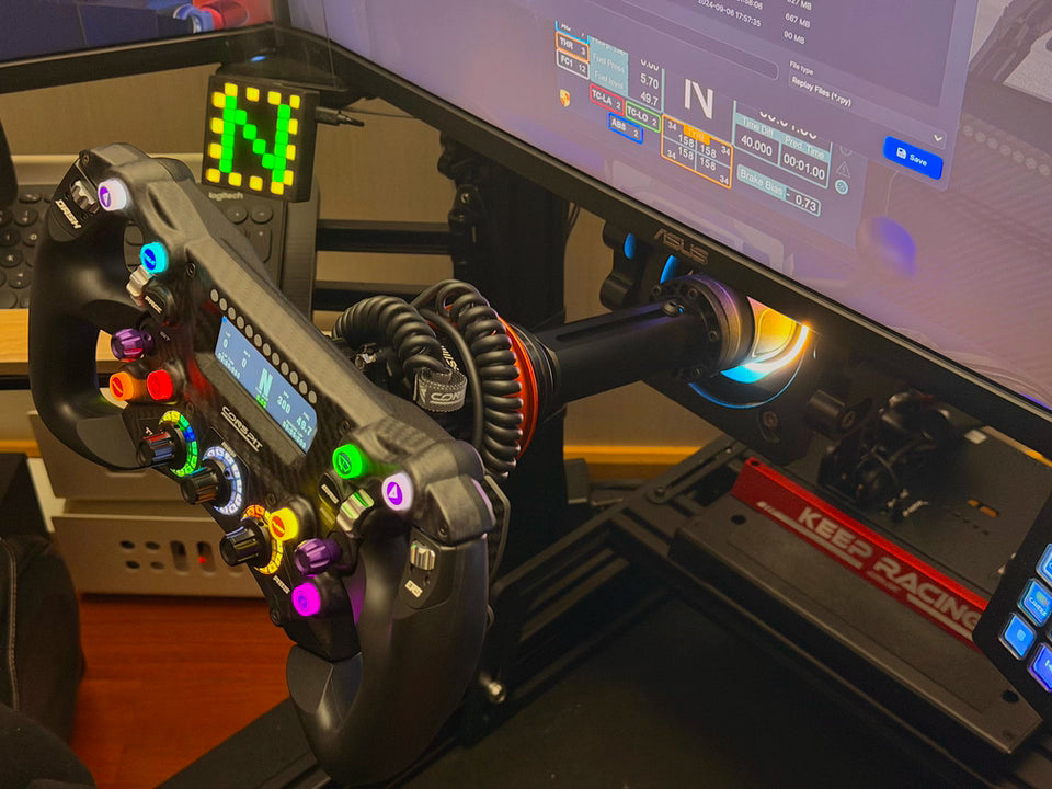 Sim racing setup with adjustable shaft extension connected to racing wheel and monitor