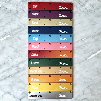KARL Extension Spacer: Stack of anodized aluminum spacers in 12 vibrant colors (Sun red, Grape purple, Sand beige, etc.) with multiple holes and KARL logo, displayed on marble.